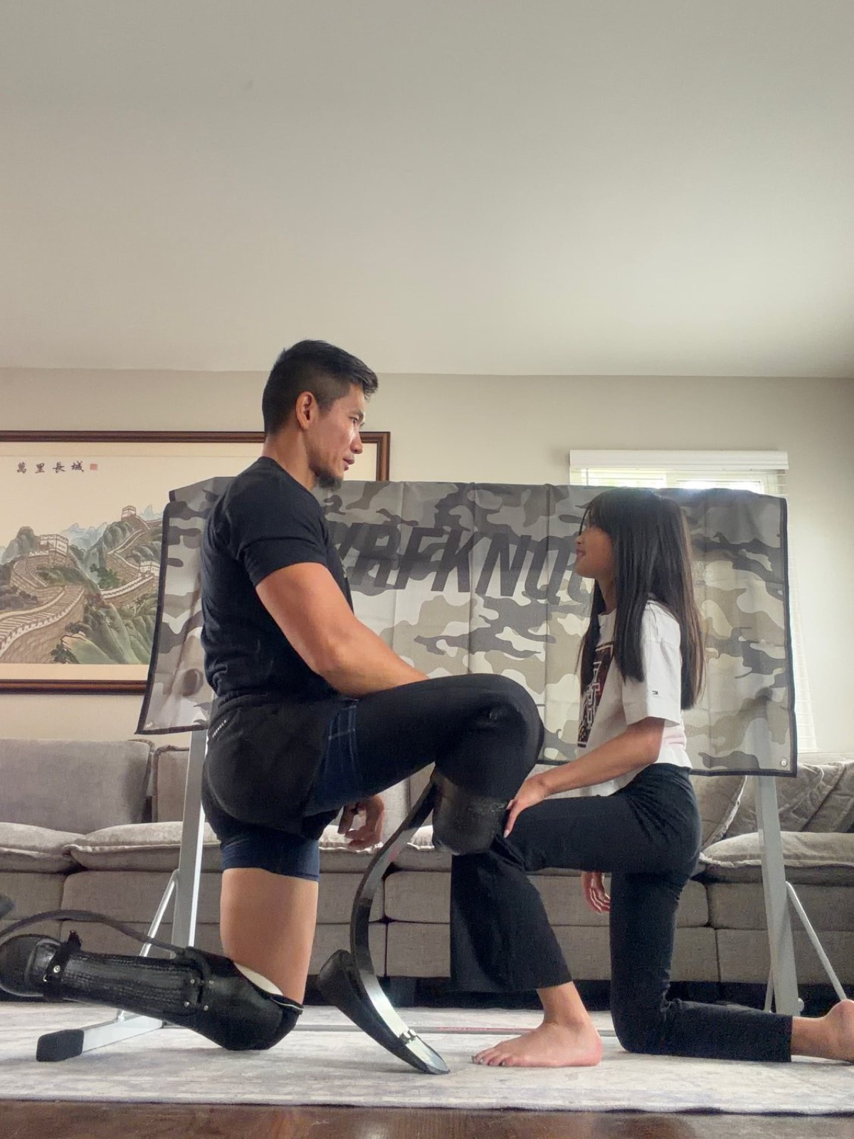 Hao Pan kneeling face to face with his daughter during a training moment