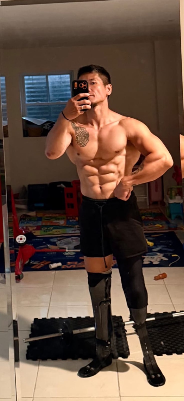 Full-body mirror photo of Hao Pan mid-training, standing on both prosthetic legs